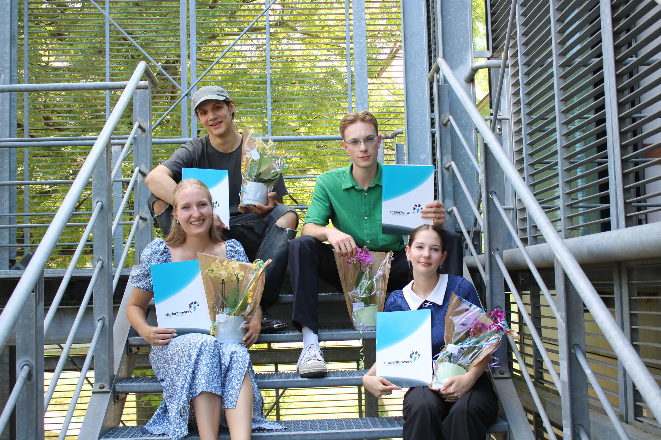 Vier Facharbeiter mit Zeugnis und Blumen