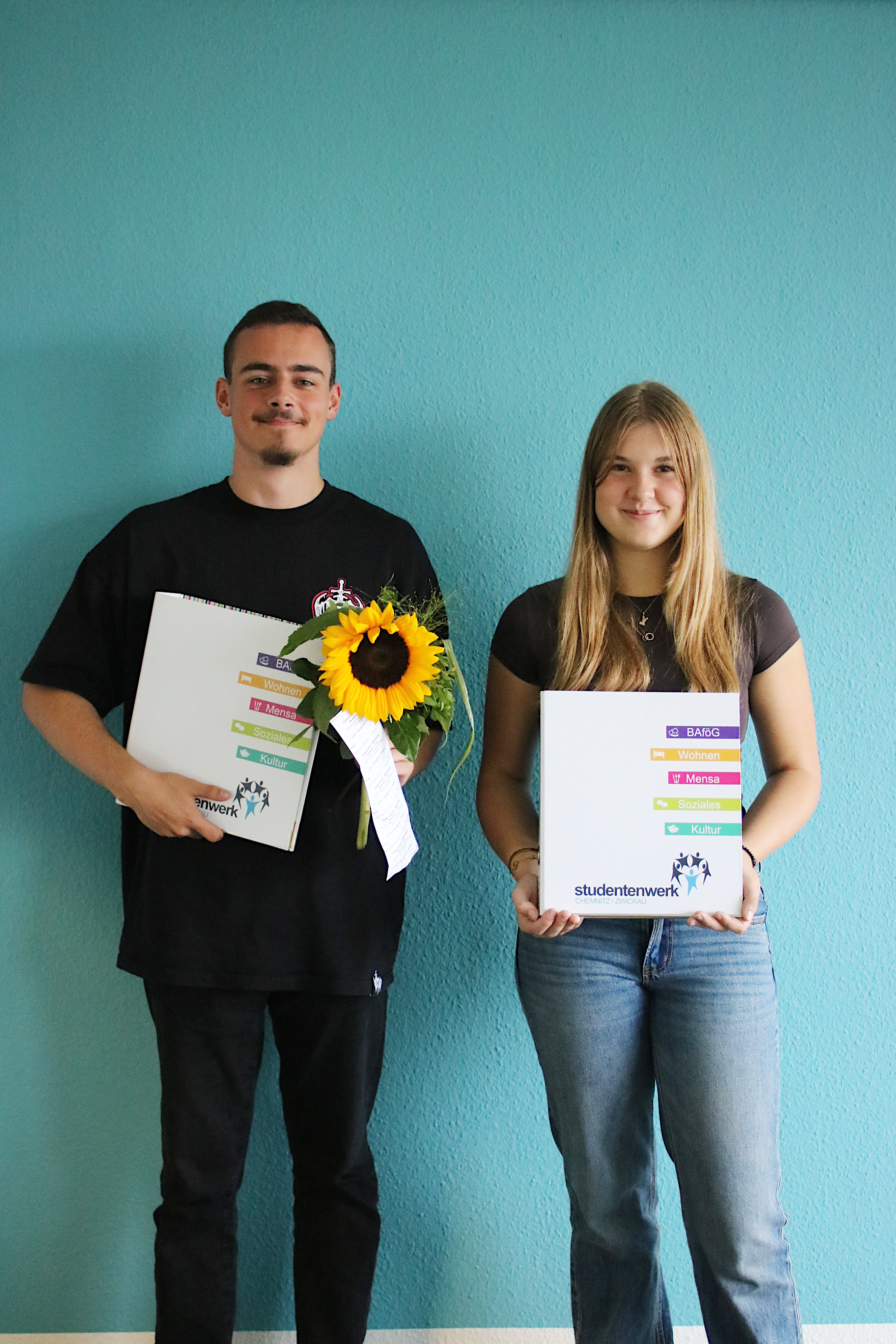 Zwei Jugendliche zum Ausbildungsbeginn mit Blumen und Mappe